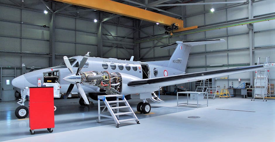 Aircraft undergoing maintenance in a spacious modern hangar.